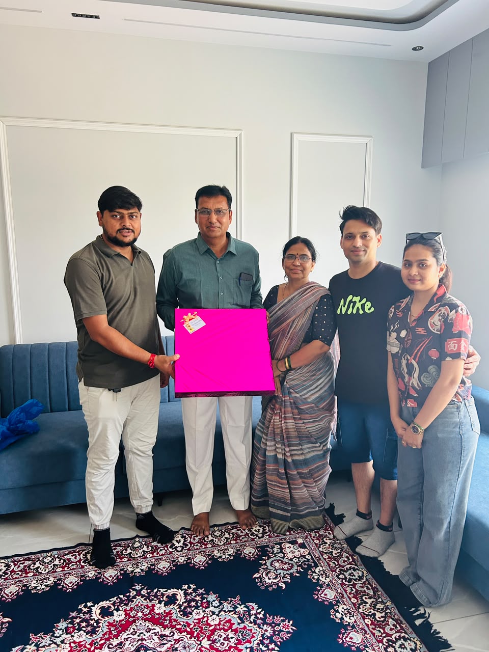 Sarvamangal representative with a family and a pink-wrapped gift in their living room